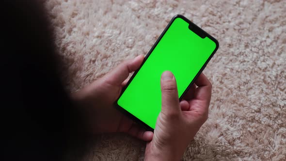 Top View of Female Lying on Floor at Cozy Apartment With Green Mockup Screen Chroma Key Surfing