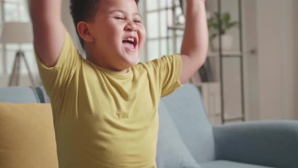 Little Boy Gamer Is Feeling Excited And Raising His Arms With Fist Gesture While Playing Game