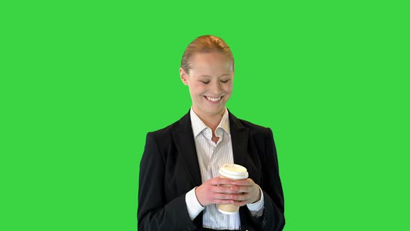 Beautiful Young Blond Business Woman Walking Holding a Cup of Coffee on a Green Screen Chroma Key
