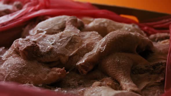 Closeup View of Hands in Gloves Packing Chicken Legs From a Box Into Individual Plastic Bags