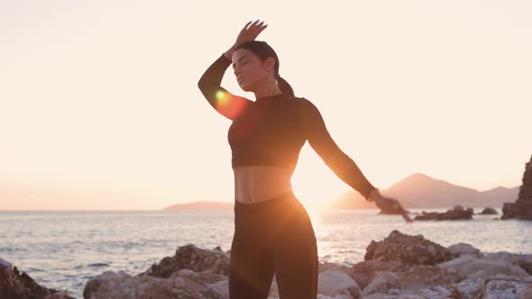 Sexy Athletic Woman Stretching Exercises on Beach at Sunset