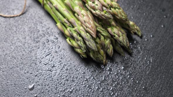 Raw Green Asparagus on Wet Black Slate Background