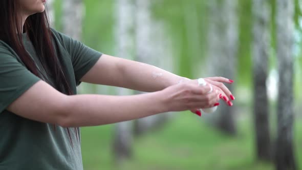 Young Woman in a Birch Grove Puts a Mosquito Repellent on Her Skin.