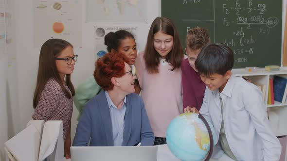 Teacher and Children Looking at Globe in Classroom