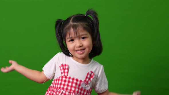 Portrait of happy and funny Asian child girl on green screen background, a child looking at camera.