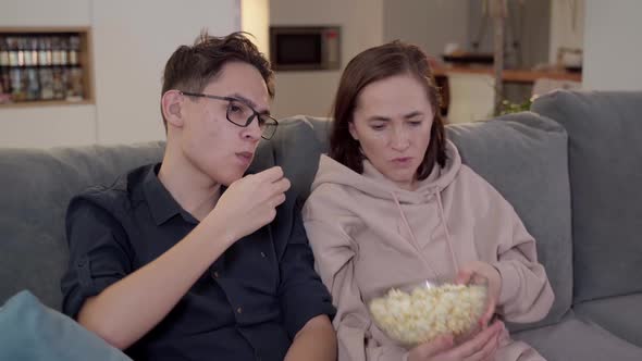 A Woman and Her Teenage Son are Watching TV and Eating Popcorn