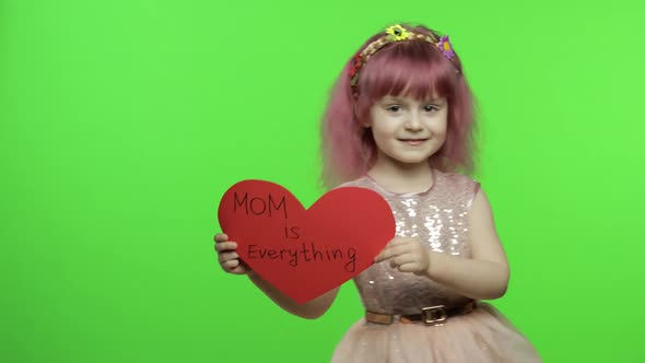 Child Girl Princess Holds Red Paper Heart with Text About Mother. Mother's Day