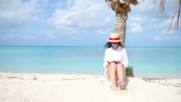 Young Woman Reading Book During Tropical White Beach