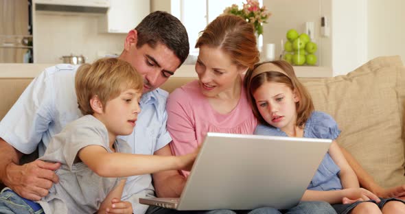 Happy young family sitting on the sofa using laptop together
