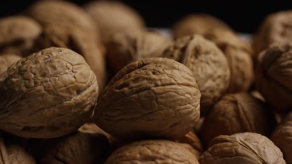 Cinematic, rotating shot of walnuts in their shells on a white surface - WALNUTS