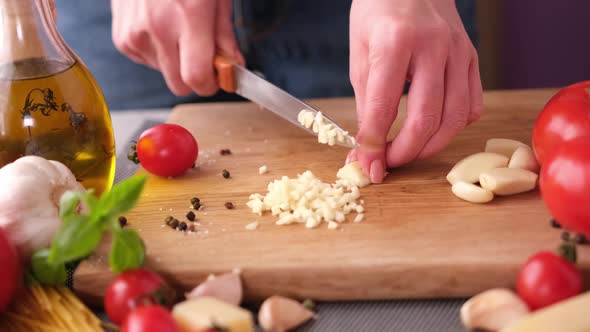 Making Pasta Carbonara  Cut Garlic with Knife on a Wooden Cutting Board