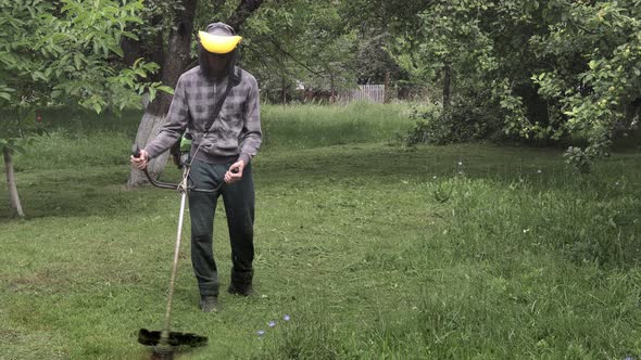 Worker with a gas mower in his hands, mowing grass in front of the house