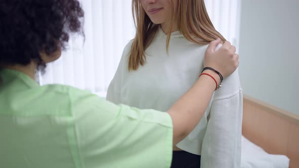 Unrecognizable Ill Woman Standing in Hospital with Doctor Nurse Tapping Shoulder Supporting Lady