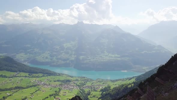 Drone flies from an incredible view backwards over a small mountain ridge where two people are stand