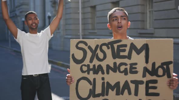 Two mixed race men on a protest march holding placards raising hands and shouting