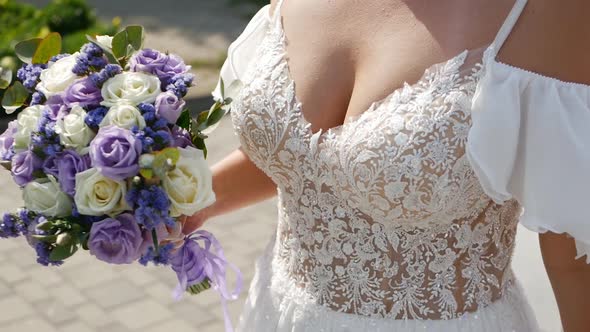 Wedding Bouquet in the Hands of a Beautiful Bride with a Large Bust