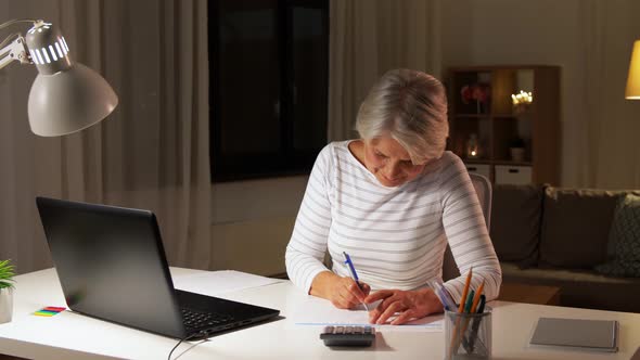 Senior Woman Filling Tax Form at Home in Evening