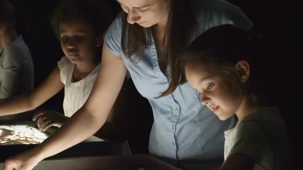 Teacher Helping Girl Making Sand Art