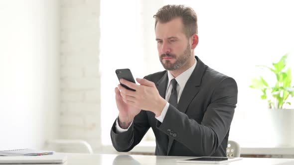 Upset Young Businessman Reacting to Loss on Smartphone