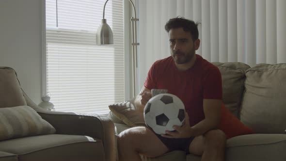 Man Holding a Soccer Ball Drinks From Mug Then Walks Out Determined