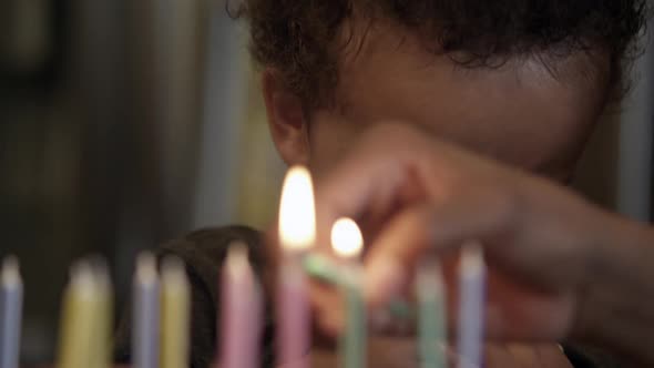 Young crying as birthday candles are lit in front of him.