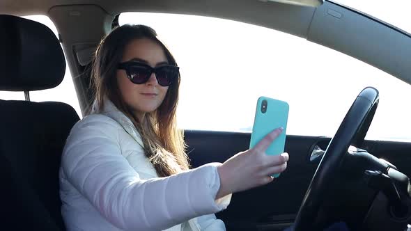 Girl Uses a Smartphone While Sitting in the Car