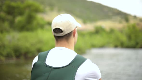 Slow Motion Shot of a Caucasian male fisherman casting his hook while Fly Fishing. He is standing in