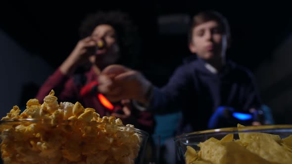 Blurry Teen Gamers Eating Popcorn and Playing Game