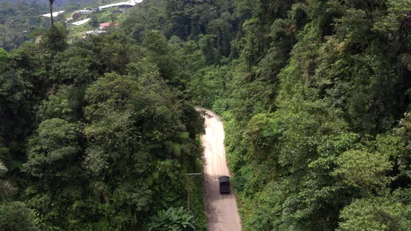 Aerial still video of a small black truck that is riding down a dirt road