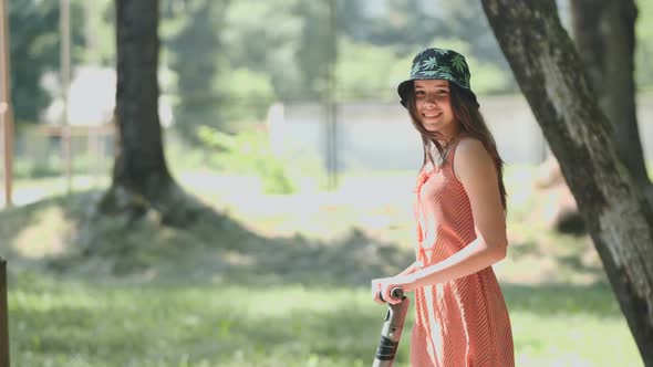 Portrait of a Girl on an Electric Scooter Riding in a Park in the Summer