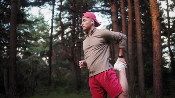 Young Asian Man Warming Up at Forest Road Before Jogging