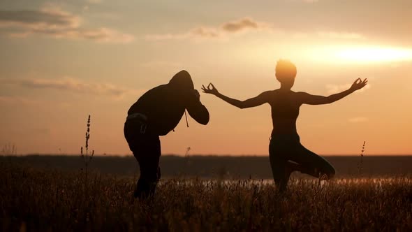 Silhouette of Young Beautiful Girl Practicing Yoga at Sunset