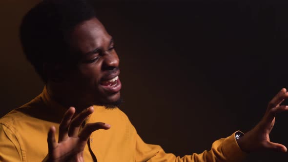 Stylish African American Man in Yellow Shirt Emotionally Sings a Song and Gestures with His Hands