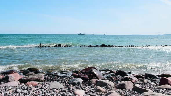 The rocky coast of the Baltic Sea and waves beat against stones on the island of Ruegen, Germany.