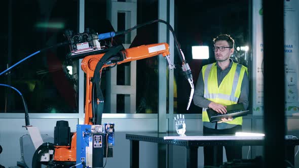 Engineer with Laptop Making Industrial Robotic Arm Ready for Arc Welding