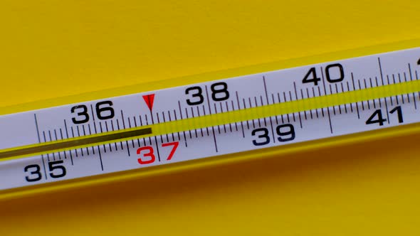 Temperature Rising Shown on a Thermometer on a Yellow Background Closeup