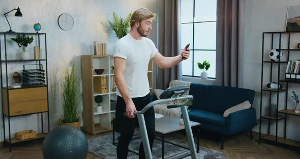 Man in Training Clothes Talking with Friend Via Video Chat and Doing Exercises on Running Track