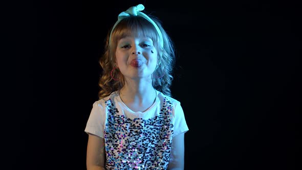 Portrait of Trendy Stylish Girl Showing Tongue Fooling Around in Neon Light at Disco Party Studio