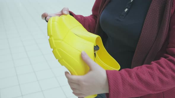 Pregnant Woman in Store Chooses Yellow Rubber Galoshes to Buy