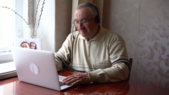 Smiling Senior Man Wear Earphones Wave to Camera Having Video Call on Laptop Happy Elderly Male in
