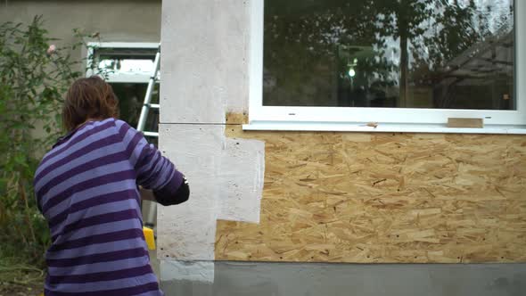 Female Worker Paints the Corner of Wooden House