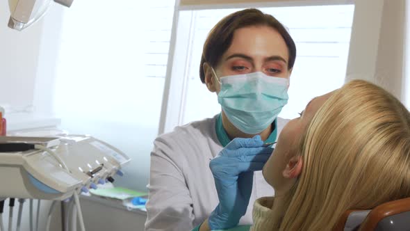 Female Dentist Working Examining Teeth of a Patient at the Clinic