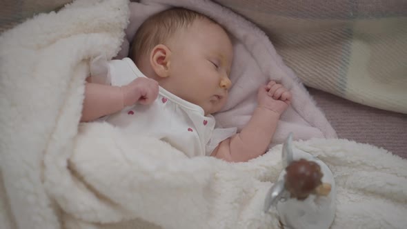 Top View Sleeping Newborn Girl Lying on Bed with Toy Angel Aside