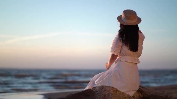 Woman in Dress Relaxing Sitting on a Big Stone in Sea