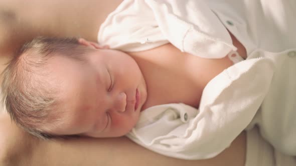 newborn baby sleeping on mother's lap top view alt
