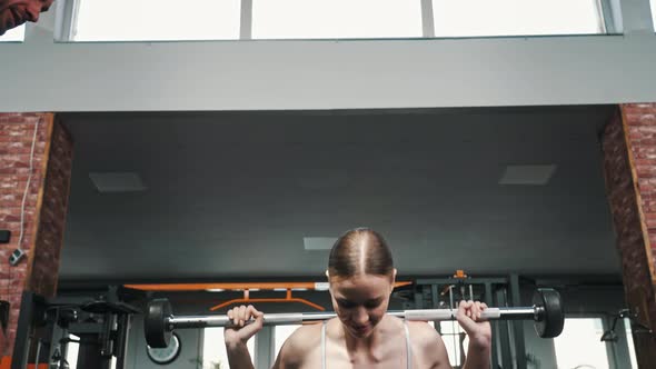 Fashionable Skinny Caucasian Girl Lifting Weights on Her Shoulders