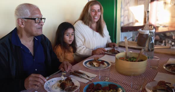 Happy latin girl having fun eating with her grandparents at home