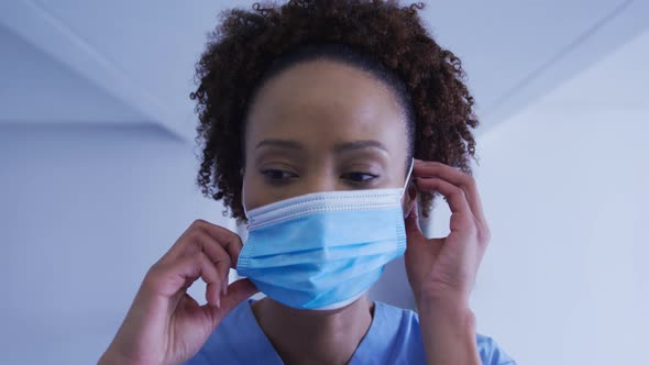 Portrait of mixed race female doctor putting face mask on