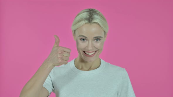 Young Woman Gesturing Thumbs Up on Pink Background