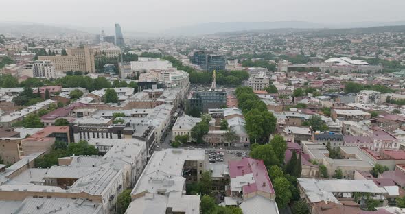 Slow aerial shot of the Tbilisi cityscape, including the St. George statue.